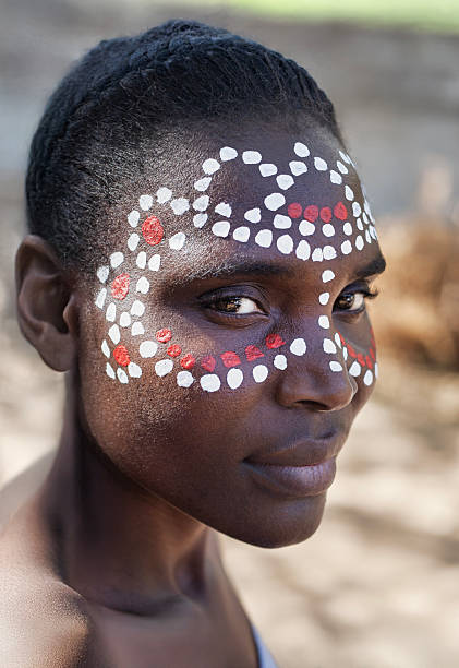 Tribal painted face pattern , single young african woman with white and red dots pattern on her face, headshot profile view