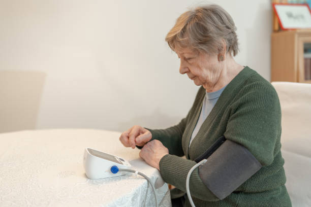 istock Senior woman measures her blood pressure while sitting at home in comfortable environment. Concept of health, wellness, self-care, medical monitoring, and senior independence. Healthcare for seniors 2201796530