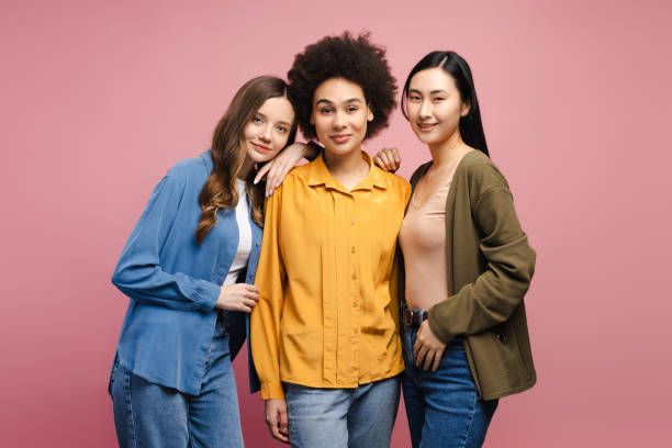 istock Three young women embracing diversity and friendship on pink background 2201797438
