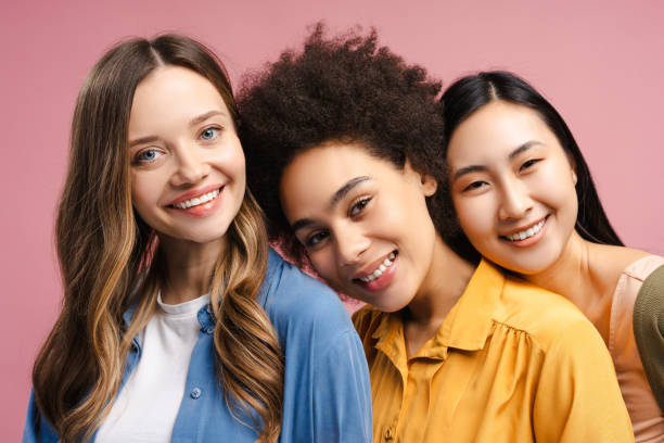 istock Three smiling young women of different ethnicities posing together on pink background 2201797449