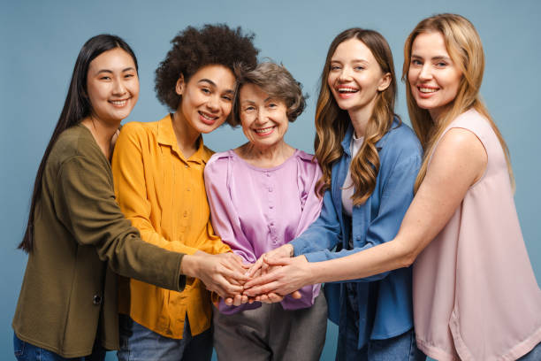 istock Five smiling women of different ages and ethnicities joining hands together 2201797469