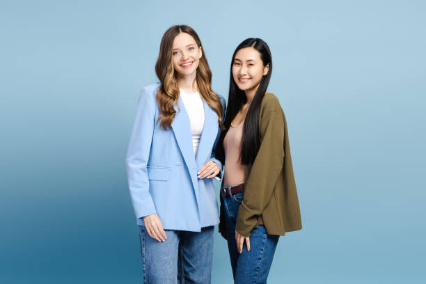 istock Two young women smiling and posing together on blue background 2201797513