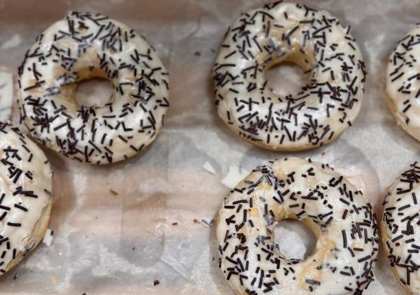 Enjoy freshly made doughnuts topped with smooth white icing and delightful black sprinkles for a tasty treat. Close-up