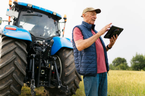 istock Senior man standing on the field behind his tractor using a digital tablet 2201798643