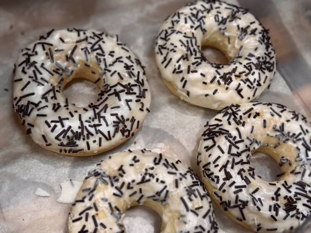 istock Enjoy freshly made doughnuts topped with smooth white icing and delightful black sprinkles for a tasty treat. Close-up 2201799331