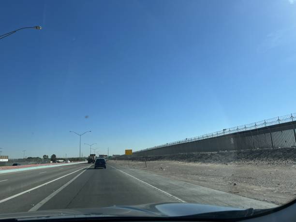istock Car window photo: US-Mexico border road.high border wall on the right. 2201799669