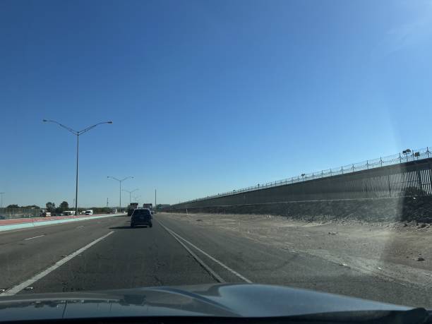 istock Car window photo: US-Mexico border road.high border wall on the right. 2201799673