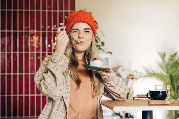 istock Cheerful young woman tasting delicious cake in modern cafe 2201800030