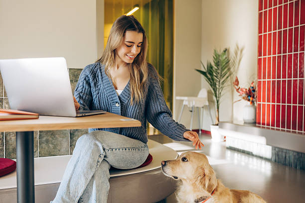 istock Freelancer woman petting her golden retriever while working from home 2201800100