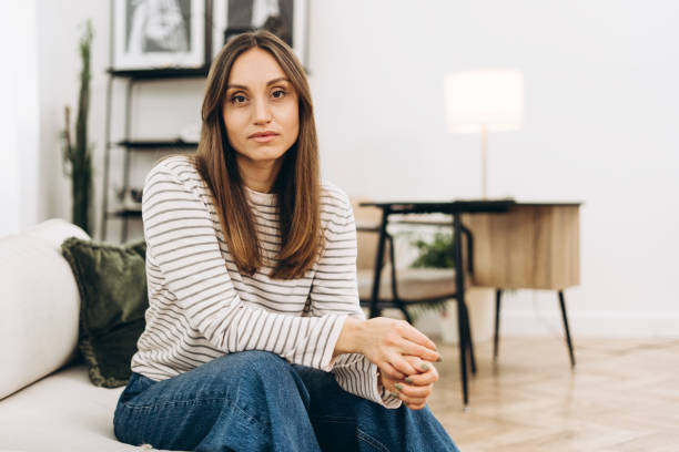 istock Young woman sitting thoughtfully on sofa in modern living room 2201801735