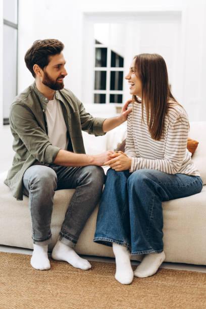 istock Young couple holding hands and talking on sofa at home 2201802176