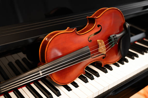 istock Violin on top of piano keyboard background 2201802604