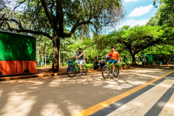 istock Father and son riding bike in a public park 2201803389