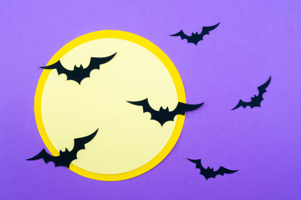 istock Halloween decorations featuring bats flying around a large moon on a purple background 2201805387