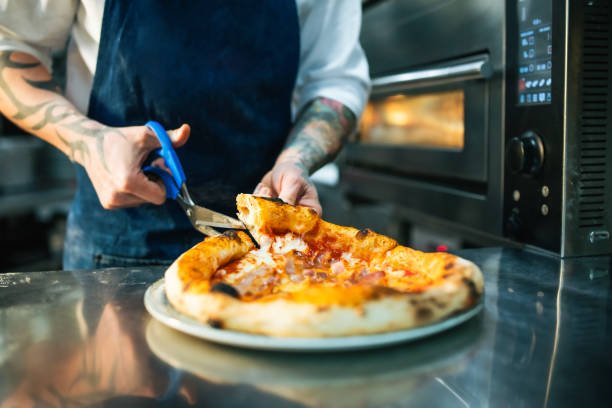 istock Pizza chef cutting up pizza in the kitchen. 2201805723