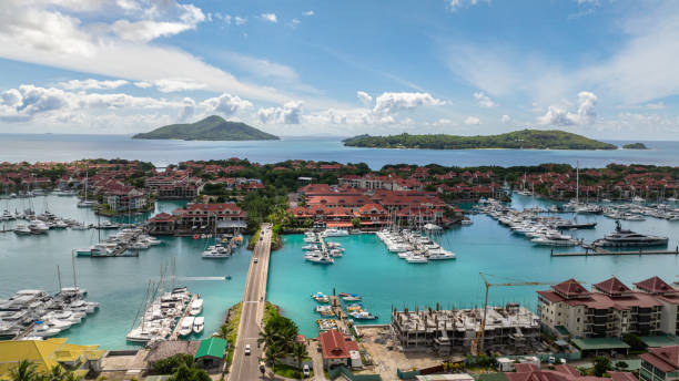 Urban settlement with buildings, roads, and lush green mountains in the background next to a coastal water body. Seychelles, Mahe.