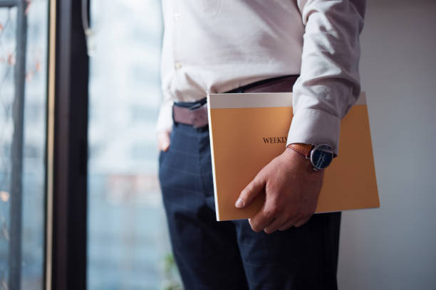 istock Professional Individual Holding a Yellow Folder by the Window Indoors 2201815605