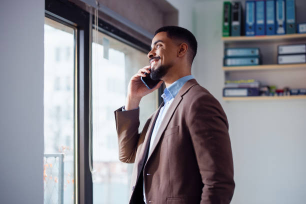 Smiling Businessman Making a Phone Call in a Bright Office Setting