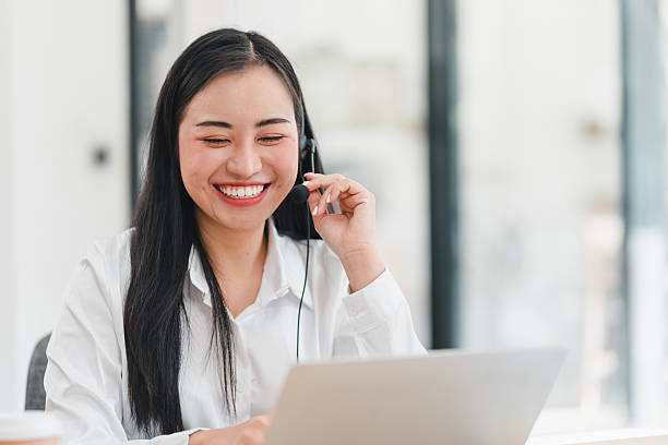 istock Smiling woman in headset working on laptop in bright office 2201826634