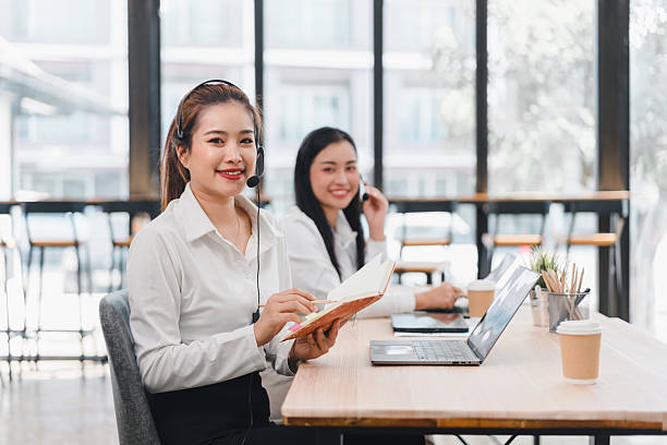 istock Smiling women in office with headsets and laptops 2201826711