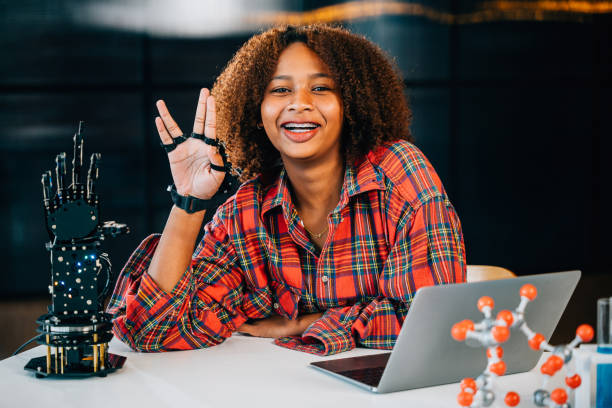 istock Black teenage student in a classroom learns and tests a robotic arm discovering subjects of interest. Embracing innovation and technology for skill development in joyful education. 2201828466