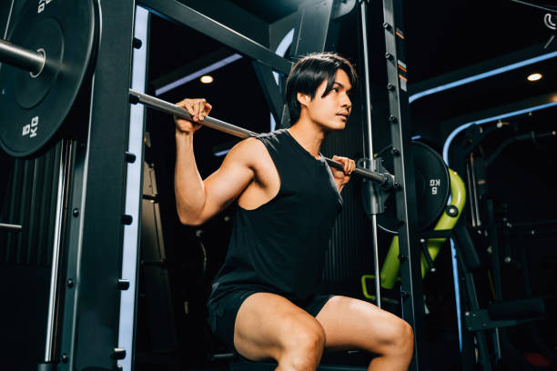 istock Asian muscular man guy performing a squat exercise legs heavy weights with a barbell in gym, men doing lifting barbell work out at fitness gym, sport workout healthy lifestyle 2201828469