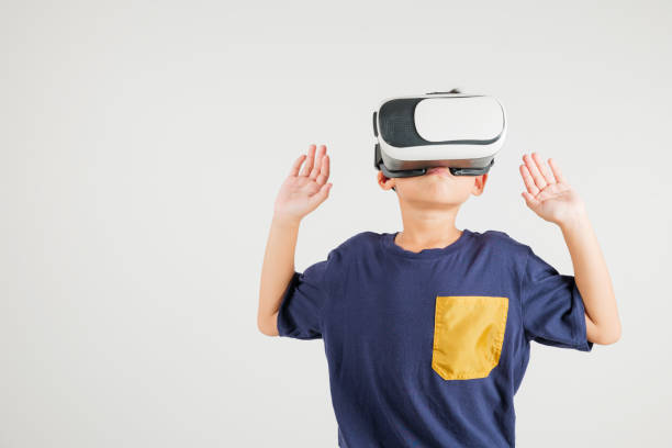 istock Portrait Asian smiling kid boy touching at something in a virtual reality glasses headset studio shot isolated white background, Excited happy primary child using VR play simulation 2201828511