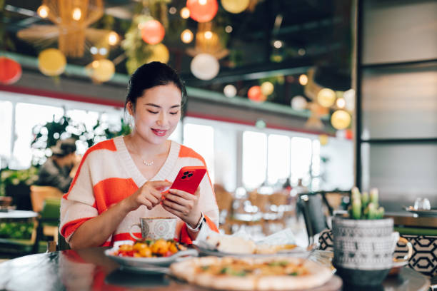 istock Asian young woman using mobile phone while sitting in a cafe having coffee. Making a personal financial plans and investment decisions. Wealth management. Business, banking, finance and investment concept. 2201829751