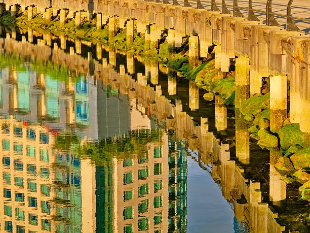View of an office tower reflection in Vancouver seen from Coal Harbor and Burrard Inlet seawall walkway, British Columbia