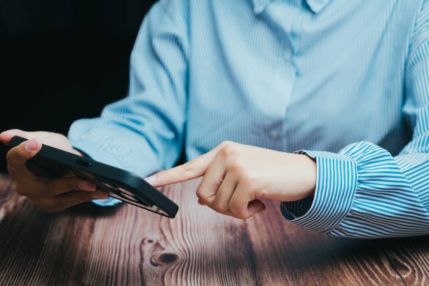 istock Person Using Smartphone on Wooden Table in Bright Indoor Setting, Business concept 2201837957