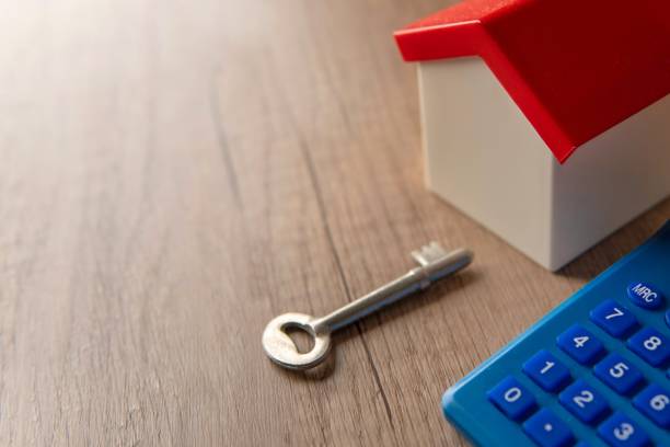 istock A toy house, a key, and a calculator on a wooden table. 2201842602