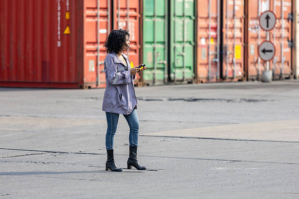 Young woman walking in industry containers cargo, Engineer in shipping container yard