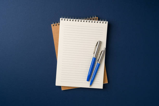 istock Top view of notebook and ballpoint pen on blue background 2201845572