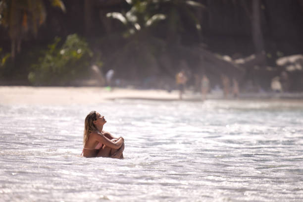 Young beautiful woman enjoying while relaxing in sea during summer day on the beach. Copy space.