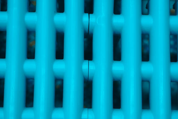 close-up shot focuses on a series of bright, light blue, cylindrical rods arranged vertically. These rods are evenly spaced and connected by thinner, darker elements, creating a grid-like pattern