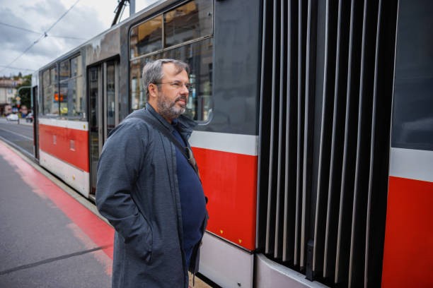 istock Middle aged man standing on tram stop in the city, tram arriving 2201849861