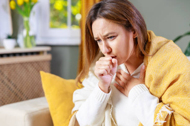istock Sick woman sitting on sofa and coughing while suffering from sore throat 2201852513