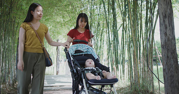 Portrait of Two young Asian women play with a little boy in a baby stroller outside a coffee shop. A relaxing atmosphere with a warm moment.