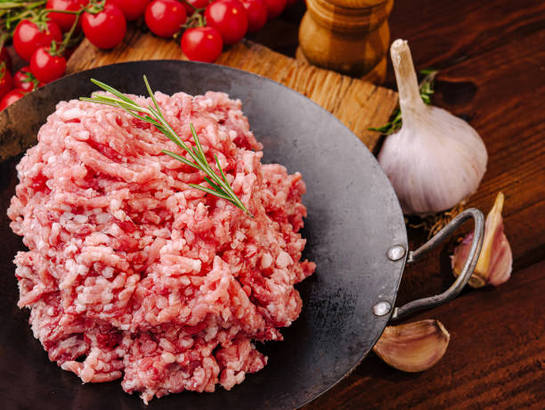 istock Freshly minced meat on a wooden table surrounded by spices and tomatoes ready for cooking 2201857104