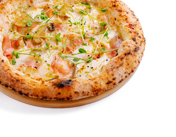A round pizza sits on a wooden board, topped with creamy cheese, fresh herbs, and an assortment of meats. The crust is golden and crispy, inviting a delicious bite.