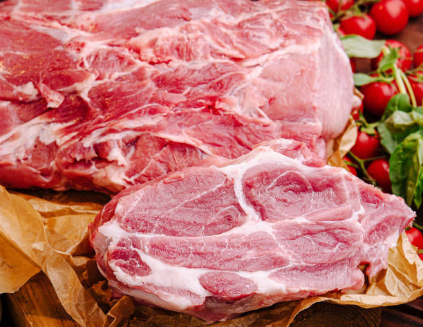 istock Fresh raw pork cuts with vegetables and spices arranged on wooden surface in kitchen setting 2201857387