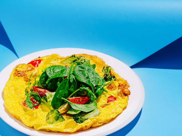 istock Delicious vegetable omelette garnished with fresh spinach on a bright blue background 2201858006