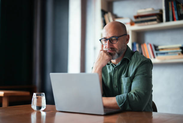 istock Focused Businessman Working on Laptop in a Cozy Library Setting 2201858175