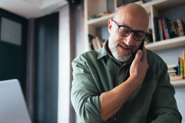 istock Smiling Mature Man Engaged in a Phone Conversation in a Cozy Office 2201858193
