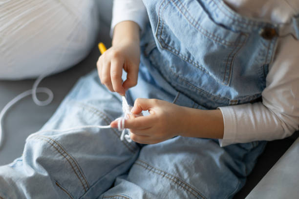 istock Child, learning crocheting, knitting, hand Crochet basics. Kid sitting at home, crocketing amigurumi figure 2201859316