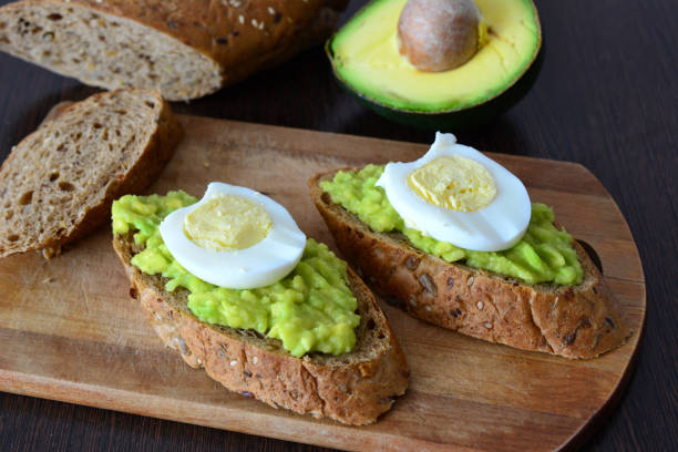 istock Avocado Toast with Egg on cutting board on wooden kitchen table 2201859717