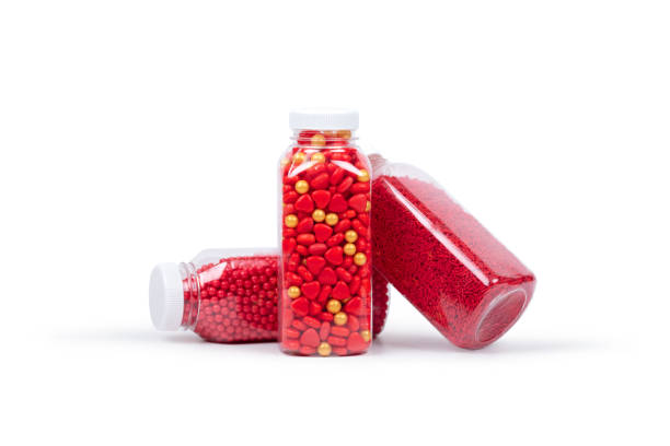 istock Three transparent plastic bottles filled with vibrant red and gold sprinkles, heart-shaped candies, and sugar pearls, isolated on a white background for baking and cake decorating. 2201859757