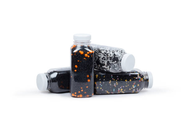 Assortment of black, orange, and dark sprinkles in transparent plastic bottles. Various textures and styles of decorative sugar elements perfect for Halloween baking, spooky desserts, and autumn-themed treats. Ideal for seasonal celebrations and creative confectionery.