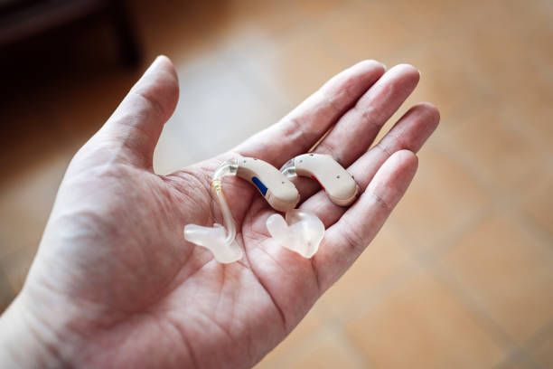 Woman holding a hearing impairment device in the hands with a white background and copy space in the left side