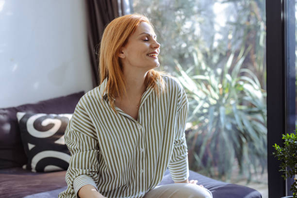 istock Woman enjoying sunshine indoors with a serene and relaxed expression 2201862324
